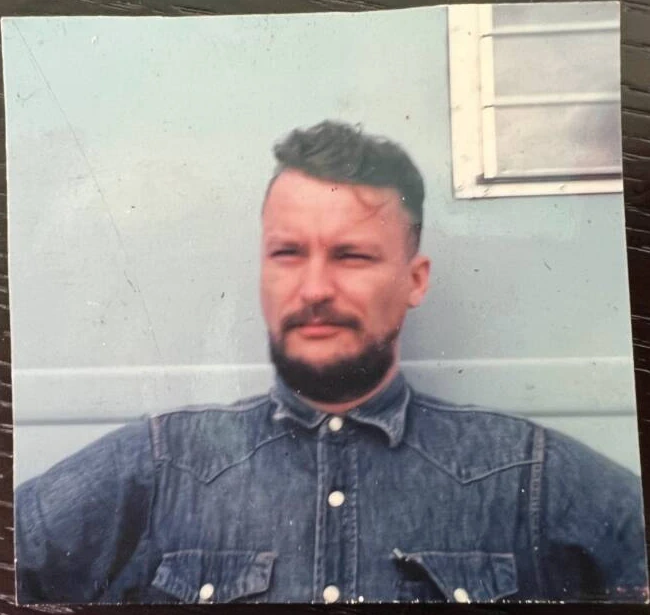 Color photograph of Paul Doerr wearing a denim shirt and standing outside a building.